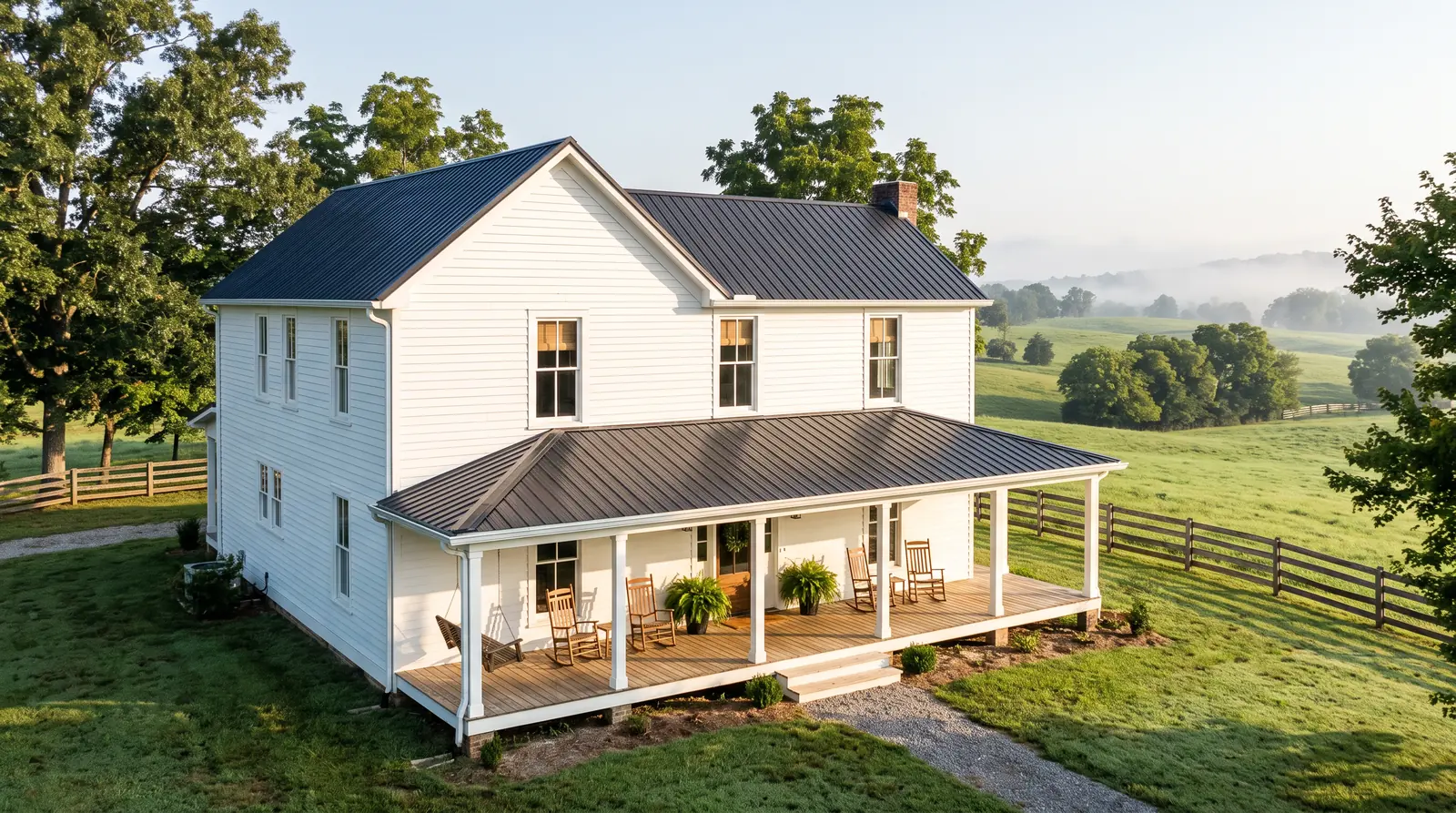 Country Home With Wide Porch and Tall Windows | Music City Blinds A white farmhouse-style home in rural Middle Tennessee with a wide covered porch, rocking chairs, tall windows with simple woven shades visible inside, rolling pastures and a wooden fence behind, soft morning light